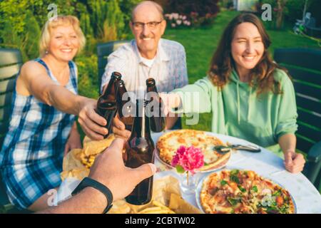 POV Bild von Menschen mit Bierflaschen auf Multi toasten Generation Familie Hinterhof Party (Fokus auf erste Flasche) Stockfoto