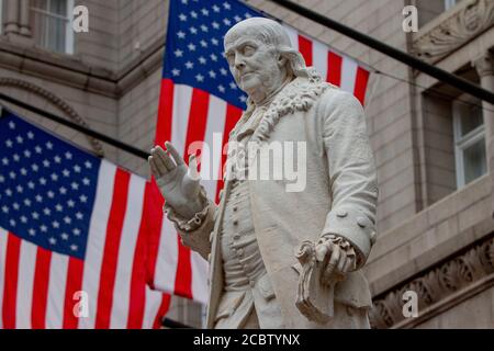 Der berühmte Wissenschaftler Benjamin Franklin war auch ein führender Schriftsteller, Drucker, politischer Philosoph, Politiker, Freimaurer, Postmeister, Erfinder, Humorist, bürgerschaftlicher Aktivist, Staatsmann und Diplomat. Er war auch einer der Gründerväter der Vereinigten Staaten von Amerika. Diese Statue von ihm steht prominent vor dem Old Post Office und Clock Tower in Washington D.C. das Old Post Office Building wurde 2013 an DJT Holdings LLC vermietet und ist heute das Trump International Hotel Washington DC. Stockfoto