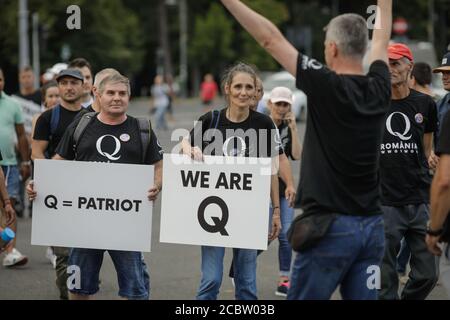 Bukarest, Rumänien - 10. August 2020: Während einer politischen Kundgebung zeigen die Menschen Qanon-Botschaften auf Kartons. Stockfoto