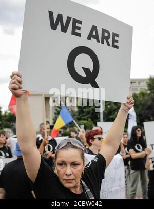 Bukarest, Rumänien - 10. August 2020: Während einer politischen Kundgebung zeigen die Menschen Qanon-Botschaften auf Kartons. Stockfoto