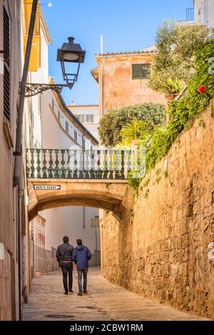 6. März 2020: Palma, Mallorca - zwei junge Männer gehen die Carrer de Can Serra hinauf, vorbei an den arabischen Bädern, in der Altstadt von Palma. Stockfoto