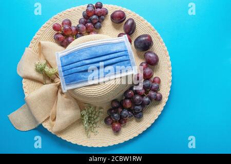 Sommerkonzept von 2020. Früchte und Blumen auf dem Rand des Sonnenhutes. Medizinische Schutzmaske. Freier Speicherplatz für Text Stockfoto