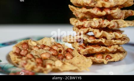 Erdnuss Peyek auf Teller. Peyek oder Peyek ist ein herzhafter javanesischer Cracker aus Reismehl mit Erdnuss Stockfoto