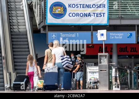 München, Deutschland. August 2020. Reisende gehen auf ein Banner am Flughafen mit der Aufschrift "Free Corona Test" zu. Am Flughafen stehen für alle Passagiere kostenlose Corona-Tests zur Verfügung. Quelle: Matthias Balk/dpa/Alamy Live News Stockfoto