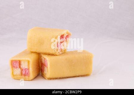 Köstliche Mini Battenberg Kuchen, die traditionelle süße Nachmittagstee Snack. Rosa und gelbe Biskuitkuchen mit Marmelade in Mandel-Marzipan gewickelt bedeckt. Stockfoto