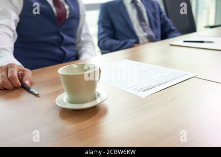 asiatische Personalverantwortliche befrachten Kandidaten, konzentrieren sich auf das Antragsformular auf dem Tisch Stockfoto