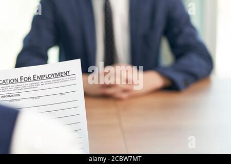 asiatische Arbeitssuchende, die von Human Resources Manager im Büro interviewt werden, konzentrieren sich auf das Antragsformular Stockfoto