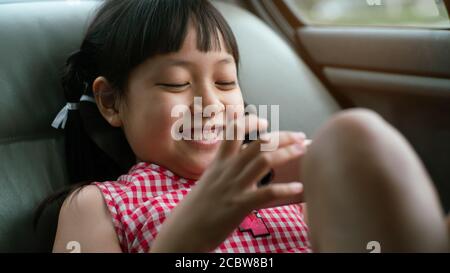 Asiatische Kind Mädchen spielen mit Smartphone im Auto.16:9 Stil Stockfoto