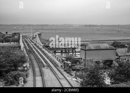 Ein schwarz-weißes Bild der Eisenbahnschwingenbrücke über den Fluss Yare im Dorf Reedham im Norfolk Broads National Park. Aufgenommen von oben stehend auf der gemauerten Eisenbahnbrücke Stockfoto