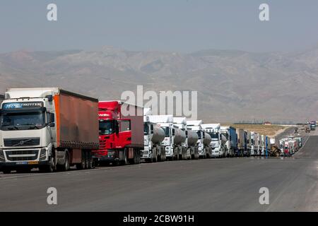 Eine lange Reihe von Sattelaufliegern und Lastwagen warten auf einer Autobahn, um einen Kontrollpunkt zu passieren, der von Dogubayazit in der Türkei in den Iran führt. Stockfoto
