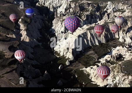 Heißluftballons schweben bei Sonnenaufgang über der spektakulären Goreme-Landschaft in der Region Kappadokien in der Türkei. Stockfoto