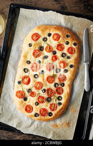 Focaccia, Pizza, italienisches Fladenbrot mit Tomaten, Oliven und Rosmarin auf Tablett Stockfoto