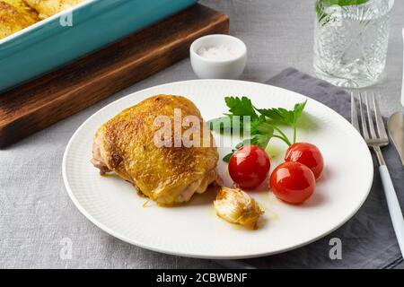 Hähnchenschenkel gebacken mit Kurkuma, Tomaten und Knoblauch. Gebratenes Huhn ist auf dem Teller Stockfoto