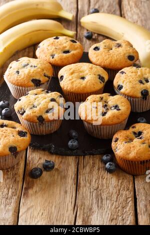 Frische Muffins mit Heidelbeeren und Bananen Nahaufnahme auf einem Schieferbrett auf dem Tisch. Vertikal Stockfoto