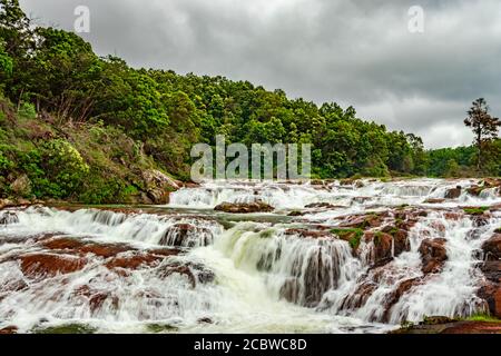 Wasserfall mit roten Felsen und grünen üppigen Wald flachen Winkel erschossen Bild ist auf Pykara See ooty tamilnadu südindien aufgenommen. Es zeigt die schöne la Stockfoto