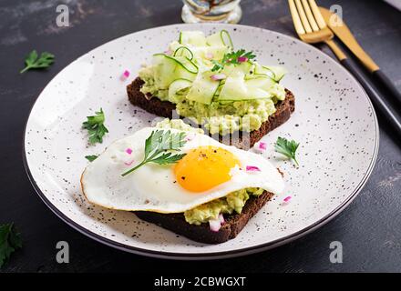 Gesundes Frühstück. Sandwich mit Avocado Guacamole, Gurke und Spiegelei, für gesundes Frühstück oder Snack. Stockfoto