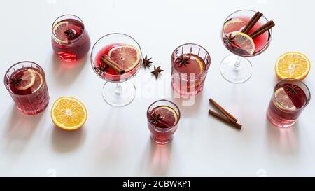 Vielzahl von vielen Gläsern Glühwein, Orangenscheiben, Zimt und Anis Sterne auf weißem Hintergrund mit Schatten. Stockfoto