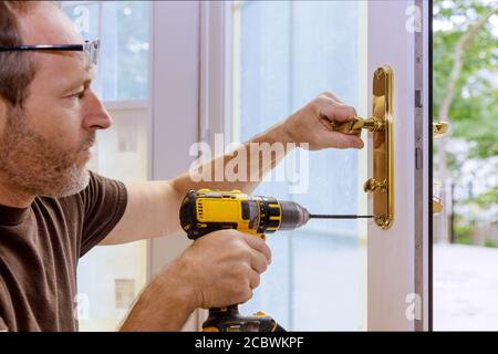 Nahaufnahme eines professionellen Bauschlosser installieren oder Reparieren eines neuen deadbolt Verschluss auf eine Haustür mit der Innenseite interne Teile des Schließmechanismus sichtbar. Stockfoto