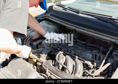 Überraschender Mechaniker schaut in das Auto. Stockfoto