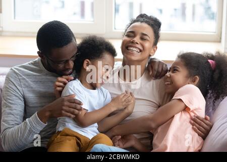 Liebevolle schwarze Eltern kitzeln und kichern mit Kindern zu Hause Stockfoto