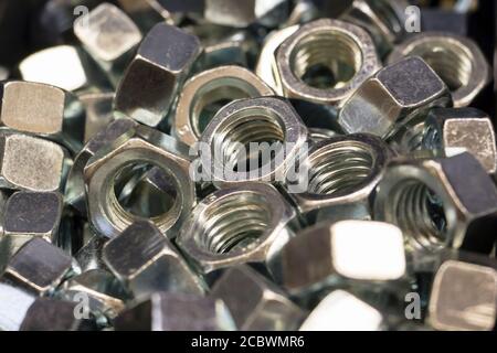 Glänzende Metallmuttern liegen im Stapel. Hintergrund. Nahaufnahme. Stockfoto