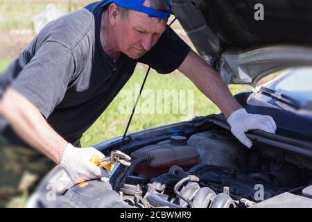 Überraschender Mechaniker schaut in das Auto. Stockfoto