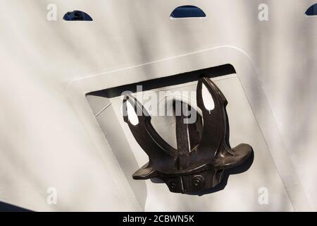 Nahaufnahme eines Ankerankers eines schwarzen Schiffes auf einem weiß gestrichenen Bogen mit einer Schusskalennummerierung. Stockfoto