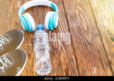 Sportausrüstung. Sneaker, Wasser und Kopfhörer auf Holzhintergrund Stockfoto