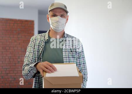 Lieferung Mann in medizinischen Gesichtsmaske mit einer Box Stockfoto