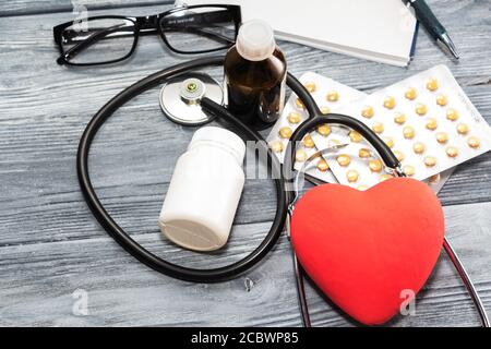 Ein Herz mit Stethoskop liegt auf einem hölzernen Hintergrund. Gesundes Herz Stockfoto