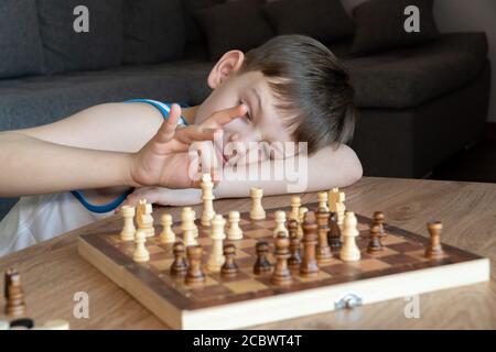 Das ernste Kind verlor im Denken, Schach zu spielen. Brettspiele spielen, auf Coronavirus Quarantäne. Das Kind, das Schach spielt. Stockfoto