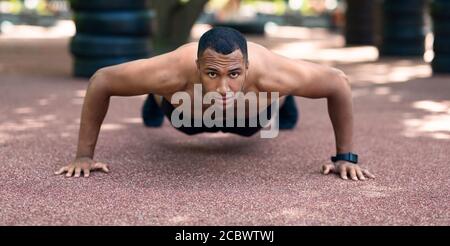 Starke schwarze Kerl tun Push-ups oder Plank Übung nach Morgens im Park laufen Stockfoto