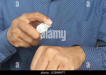 Nahaufnahme der Hand eines jungen Mannes mit Handdesinfektionsspray. Stockfoto