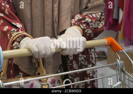 Frau in Schutzhandschuhen mit Einkaufwagen. Stockfoto