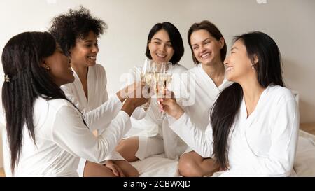 Multirassische Mädchen mit Sektgläsern, die im Hotelzimmer hängen Stockfoto