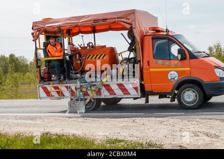 Eine Markiermaschine trägt horizontale Markierungen auf einer Straße mit Farbe auf. Stockfoto