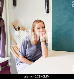 Business woman sitting at table and smiling in ceramic workshop. Young businesswoman at pottery Stockfoto