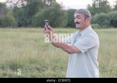 Muslimischer älterer Mann, der Fotos auf einem Handy gemacht hat Stockfoto