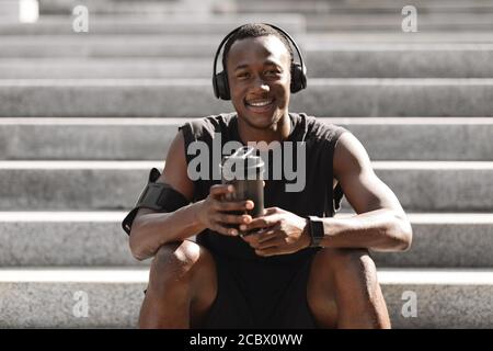 Black Guy Ruhe Nach Joggen Im Freien, Musik Hören Und Mit Protein Drink Stockfoto