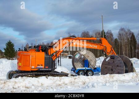 Orange Hitachi Zaxis 225 US LC-Bagger und Kabelrollen auf verschneite Ausgrabungsstätte im Winter, Finnland Stockfoto