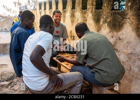 Gruppe von Musilm Männer spielen carrom, tragen traditionelle Kleidung genießen Freizeit in Lamu Insel Stadt Stockfoto