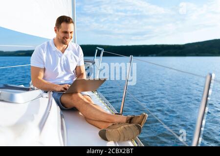 Glücklicher Mann Auf Yacht Sitzen Mit Laptop Arbeiten Auf Segelboot Stockfoto