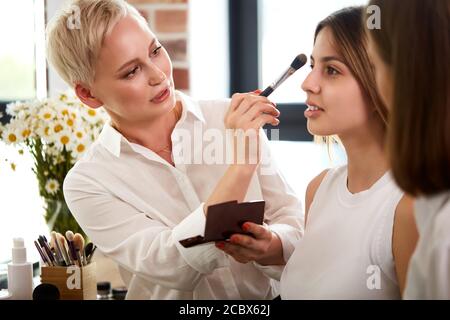 Professionelle Make-up-Lehrer, visagiste mit ihrem Schüler Mädchen Anwendung Make-up auf die Augen in der Meisterklasse in der Beauty-Schule Stockfoto