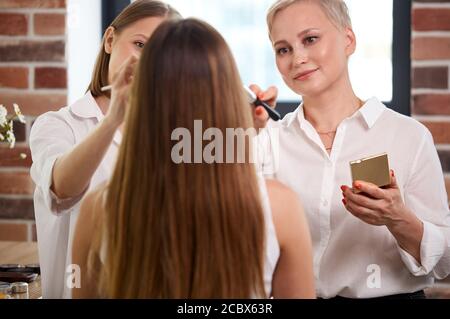 Professionelle Make-up-Lehrer, visagiste mit ihrem Schüler Mädchen Anwendung Make-up auf die Augen in der Meisterklasse in der Beauty-Schule Stockfoto