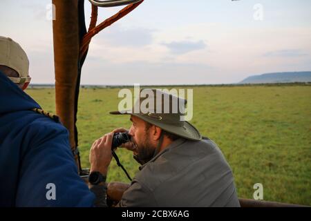 Heißluftballons treiben bei Sonnenaufgang über die ostafrikanische Savanne und bieten einen atemberaubenden Blick auf das kenianische Buschland und die Akazienbäume aus der Luft. Stockfoto