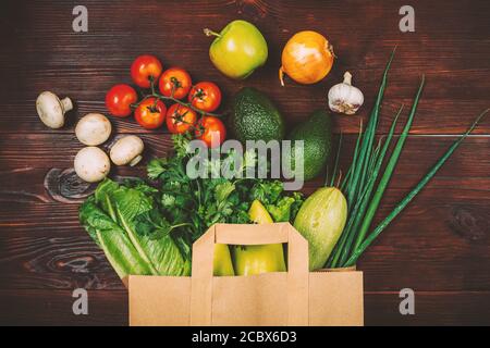 Frisches Bio-Gemüse und Gemüse für gesunde Ernährung in Papiertüte auf Holztisch, Draufsicht. Stockfoto