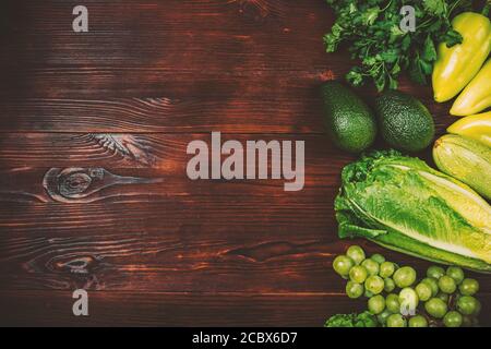 Gesunde Ernährung Hintergrund frisches grünes Gemüse, Kräuter und Früchte auf dunkelbraunem Holztisch. Stockfoto