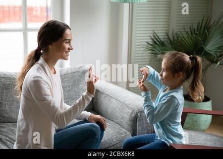 Lächelnd junge Frau Lehre kleine niedliche Mädchen Zeichen Sprache. Stockfoto