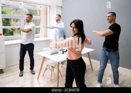 Gruppe der Glückliche junge Geschäftsleute tun Stretching Übung im Büro Stockfoto