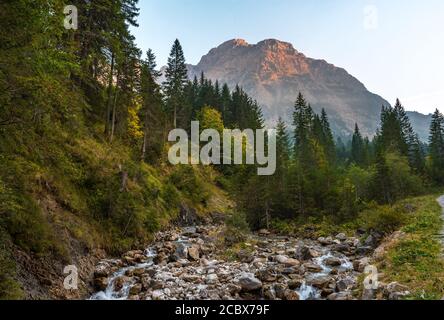 Sonnenuntergang in Österreich, Land Vorarlberg mit dem Widderstein im Hintergrund und einem Bach im Vordergrund. Stockfoto